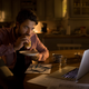 Man eating a burrito while staring at a laptop